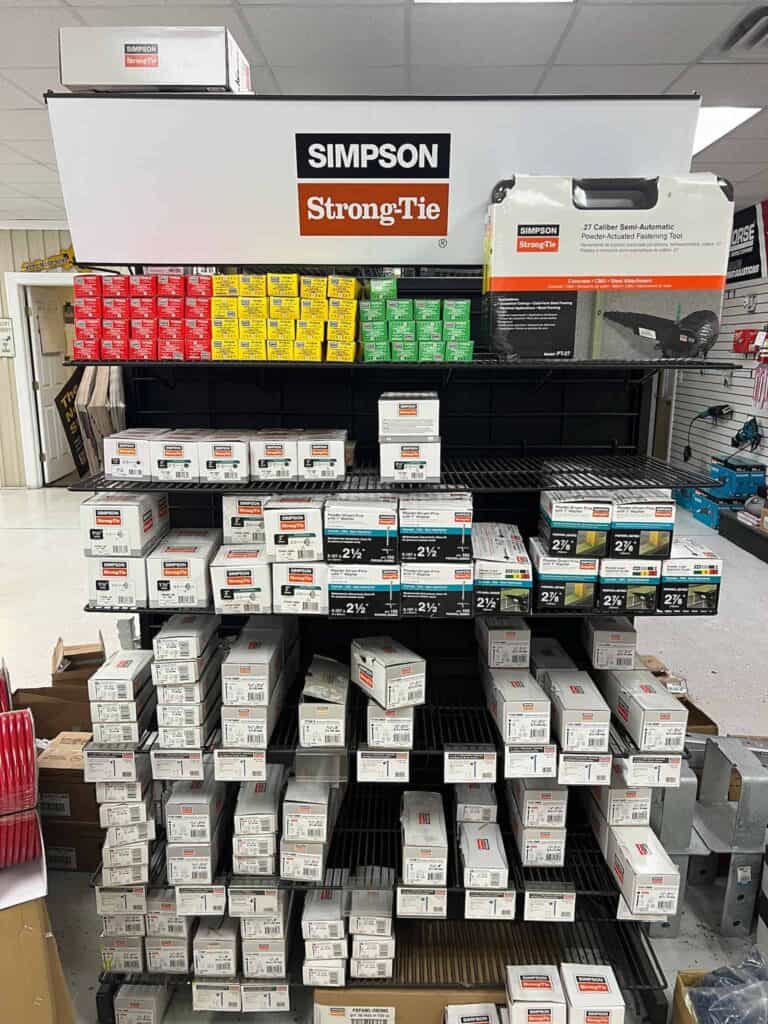 A store display at Scott's Hill Hardware features various boxes of Simpson Strong-Tie fasteners, neatly organized on shelves with a prominent Simpson Strong-Tie sign overhead.