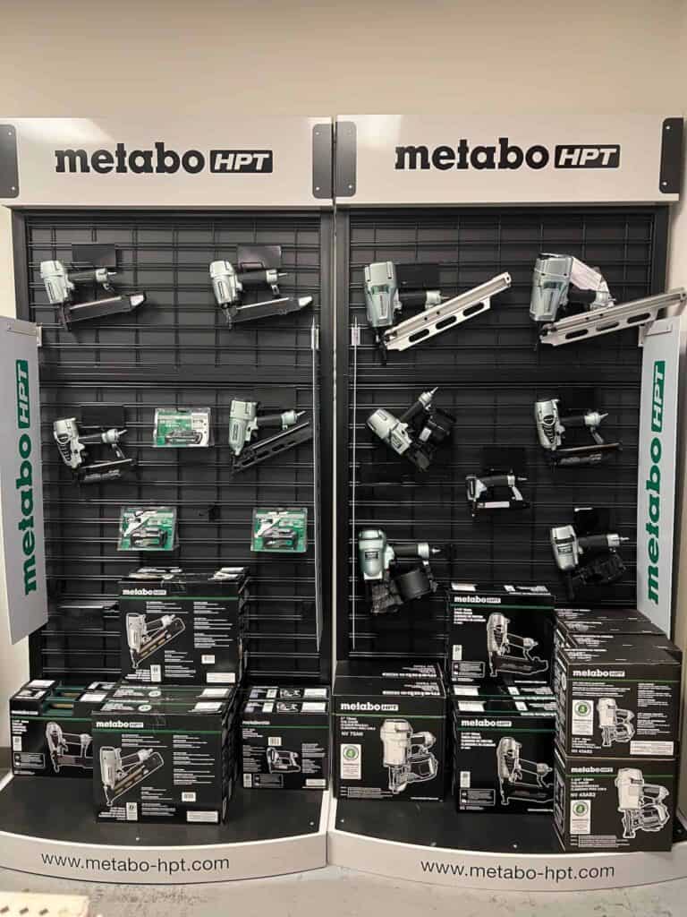 Display of Metabo HPT power tools, including nail guns, on a wall at Scott's Hill Hardware with a variety of boxed items on shelves below.