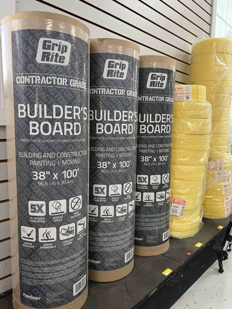 Three rolls of Grip Rite Builder's Board are displayed vertically on a shelf next to yellow insulation rolls at Scott's Hill Hardware. The Builder’s Board measures 38 inches wide by 100 feet long and is contractor grade.