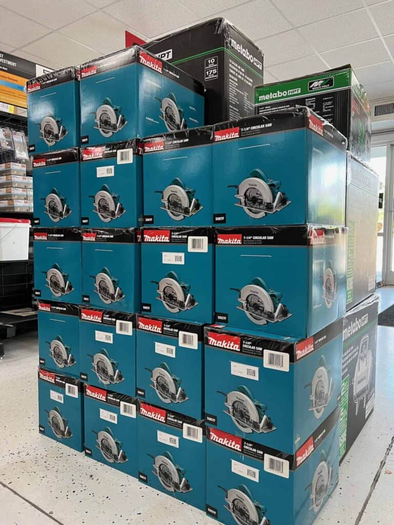 Stacks of boxed Makita circular saws displayed on pallets inside Scott's Hill Hardware, with some Metabo boxes visible in the background.