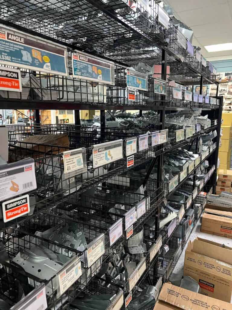 Shelves filled with various metal brackets and construction hardware line the aisle at Scott's Hill Hardware, offering a wide array of supplies for your next project.