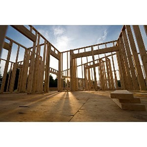 Wooden framework of a house under construction, courtesy of Scott's Hill Hardware, with sunlight casting shadows through the structure against a blue sky.