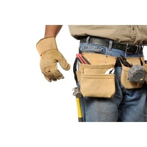 A person wearing work gloves and a tool belt filled with tools from Scott's Hill Hardware, including a hammer, pliers, and a tape measure, secured in the pouches.