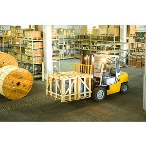 A yellow forklift from Scott's Hill Hardware transports a large, crated item in a warehouse filled with shelves stocked with various goods and materials.