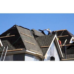 Workers from Scott's Hill Hardware are installing shingles on a residential roof using safety gear and ladders on a sunny day.