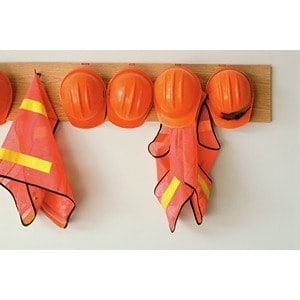 At Scott's Hill Hardware, orange hard hats and reflective vests hang on wooden hooks mounted to a wall.